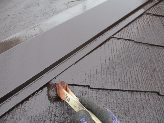 棟板金とコロニアル屋根材の取り合いを刷毛塗装中です